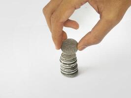 The hand is stacking Indonesian rupiah coins, isolated with a white background. photo