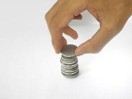 The hand is stacking Indonesian rupiah coins, isolated with a white background. photo