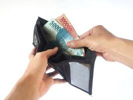 A man's hand takes and shows money from a wallet isolated on white background, rupiah is the currency of Indonesia photo