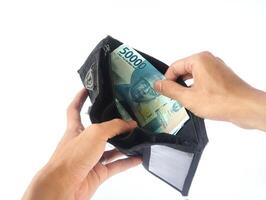 A man's hand takes and shows money from a wallet isolated on white background, rupiah is the currency of Indonesia photo