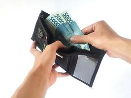 A man's hand takes and shows money from a wallet isolated on white background, rupiah is the currency of Indonesia photo