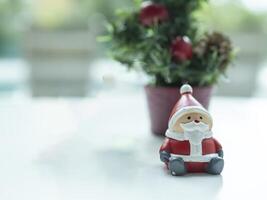 Lonely Santa Clause sitting in front of blurred Christmas trees on black background to created greeting card , Happiness and funny Christmas and New Year concept photo