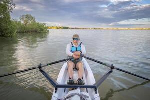 senior man in a rowing shell on a calm lake in Colorado in summer scenery photo