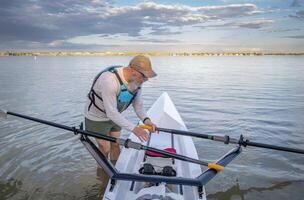 senior man in a rowing shell on a calm lake in Colorado in summer scenery photo
