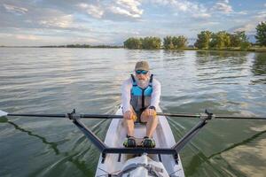 senior man in a rowing shell on a calm lake in Colorado in summer scenery photo