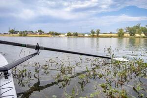 hatchet sculling oar on a calm lake with water weeds, Boyd Lake in Colorado photo
