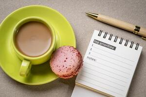 top priorities, notes in a small spiral notebook or calendar with a cup of coffee, time management concept photo
