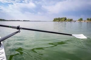 hatchet sculling oar and a rowing shell on a calm lake in summer, Boyd Lake in Colorado photo
