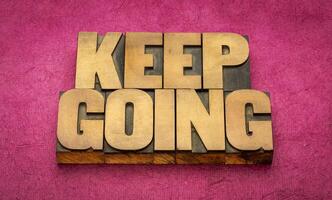 Keep going motivational word abstract in vintage letterpress wood type blocks, determination, persistence and tenacity concept photo