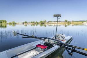 Coastal rowing shell with oars and mirror on Boyd Lake in COlorado, summer scenery photo