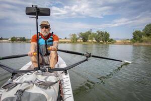 senior man in a rowing shell on a calm lake in Colorado photo