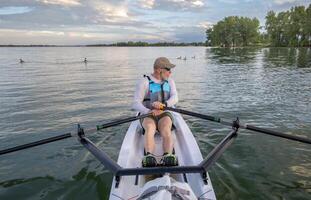 senior man in a rowing shell and Canadian geese on a calm lake in Colorado in summer scenery photo