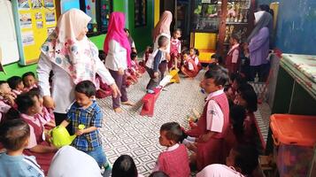 Semarang, Indonesia - July 24, 2024 - Kindergarten teacher with a group of cute little children who are playing and learning photo