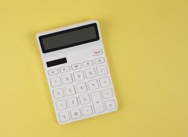 flat lay of white calculator on yellow background with copy space. photo