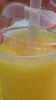 Droplets falling in a transparent glass of refreshing mango milkshake juice Summer drink India. Closeup shot of sliced yellow juicy mango and a few ice cubes kept together against a white backg... video