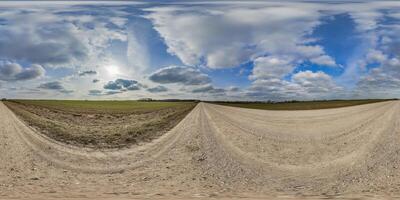 hdri 360 panorama on gravel road among fields in spring evening with awesome clouds in equirectangular full seamless spherical projection, for VR AR virtual reality content or sky replacement photo