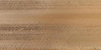 view from above on texture of dry muddy road with tractor tire tracks in countryside photo
