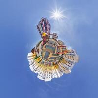 abstract swirling tiny planet spherical panorama of multi-storey buildings of skyscrapers of a residential complex in the form of a butterfly, bugs, crabs in blue sky photo