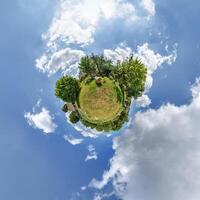simple little tiny planet without buildings in blue sky with beautiful clouds. Transformation of spherical panorama 360 degrees. Spherical abstract aerial view. Curvature of space. photo