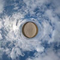 simple little tiny planet without buildings in blue sky with beautiful clouds. Transformation of spherical panorama 360 degrees. Spherical abstract aerial view. Curvature of space. photo