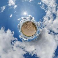 simple little tiny planet without buildings in blue sky with beautiful clouds. Transformation of spherical panorama 360 degrees. Spherical abstract aerial view. Curvature of space. photo