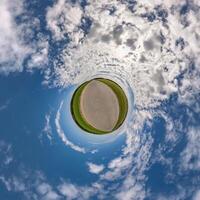 simple little tiny planet without buildings in blue sky with beautiful clouds. Transformation of spherical panorama 360 degrees. Spherical abstract aerial view. Curvature of space. photo