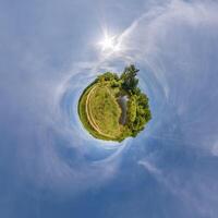 simple little tiny planet without buildings in blue sky with beautiful clouds. Transformation of spherical panorama 360 degrees. Spherical abstract aerial view. Curvature of space. photo