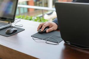 hand of businessman touching a computer mouse with laptop computer photo