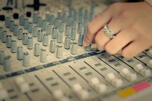 finger of engineer or music producer controlling sound recording studio mixing desk photo