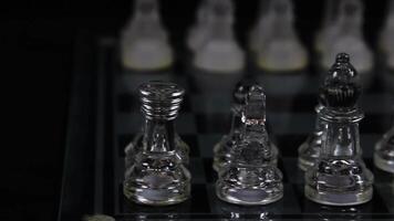 Camera Moving Behind Glass Chess Pieces In Starting Position On Board With Black Background video