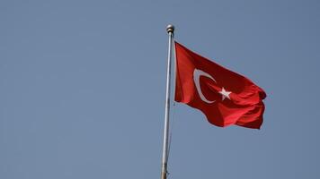 Turkish national flag on blue sky background. The flag on a flagpole flutters in the wind. The white star and crescent moon on red background. video