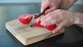 Man cutting tomatoes for salad on wooden board with kitchen knife Healthy Meal video