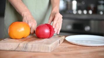 Close up shot of chef's hands cutting a fresh tomato with knife on wooden board. Cooker preparing vegetarian salad in kitchen Healthy Meal video