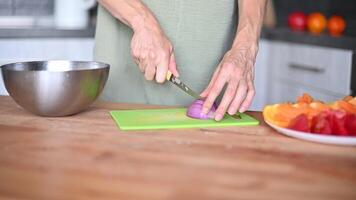 closeup being chopped with a chef knife on a cutting board woman cuts onion holding it with her fingers vegetables video