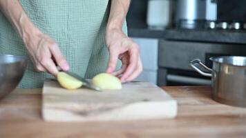 Slicing potatoes. Close-up of a knife cutting cooking vegetables. Cooking food. A woman cuts fresh potatoes the process of preparing dinner at home on a wooden kitchen board video
