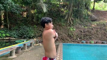 asian man stretching his arm before swimming in the nature pool, healthy lifestyle concept video