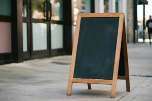 Outdoor scene with wooden A frame chalkboard, storefront, person in distance photo