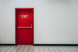 Minimalist image of red door labeled EXIT, white wall, tiled floor photo