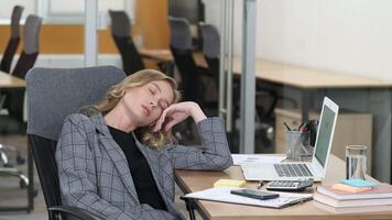 Professional woman fell asleep while working on her office. Young woman sleeping in her hand while sitting in the chair and waking up, she continue working using laptop. video