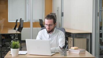 Professional working on his laptop remove his eyeglasses and massaging his head with hands. A man having a headache while working in modern office. video