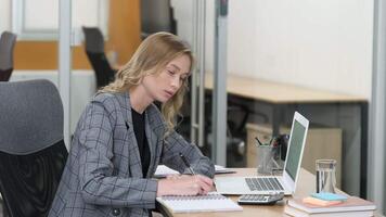Side view of busy businesswoman working in her table in a modern office. Woman calculating and taking notes. video