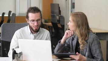 Two professionals collaborating on a project using different devices. Businesspeople engaged in problem-solving at a shared desk. video