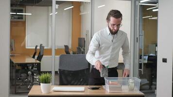 Businessman putting his personal stuff inside the plastic storage box. He clear the desk after work and put his laptop on the top of the box. video