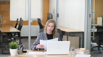 Concentrated businesswoman checking and comparing each marketing report, analyzing statistics data in charts. Young woman working on computer alone in modern office. video