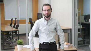 Business man standing in front of his table in modern office. A man leaning himself in the from of his table. video