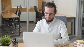 A serious and focus male worker working on his laptop. Hardworking employee, focus on typing and analyzing on computer on his desk. video