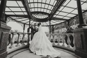 A bride and groom are kissing in front of a gazebo. Scene is romantic and intimate photo