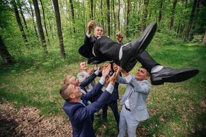 A group of men are playing in the woods, one of them is lifting another man's foot photo