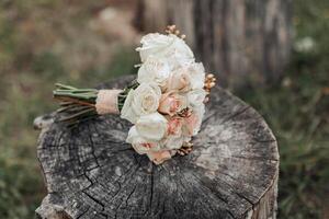 A bouquet of white flowers sits on a log. The flowers are arranged in a way that they are all facing the same direction. The log is surrounded by grass, giving the scene a natural and peaceful feel photo