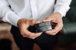 A man is holding a wallet in his hand. The wallet is black and has a silver zipper photo